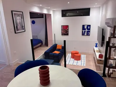 a living room with a table and blue chairs at Appartement Thème Années 60' l Baignoire Jets l Clim l Netflix in Castres