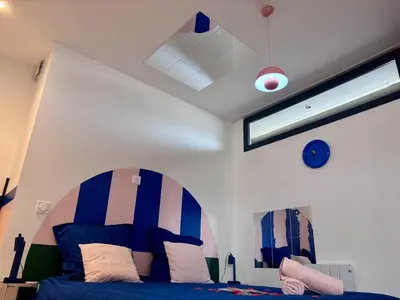 a bedroom with a bed with blue and white stripes at Appartement Thème Années 60' l Baignoire Jets l Clim l Netflix in Castres