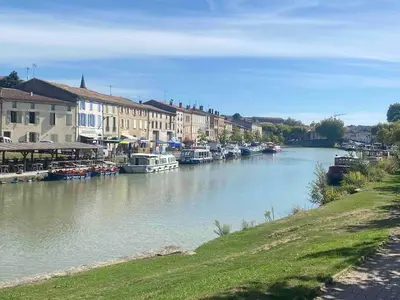 a river with boats in a town with buildings at Ferrabouc in Mas-Saintes-Puelles