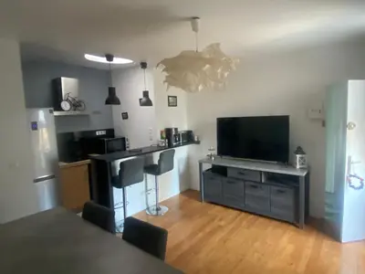 a living room with a flat screen tv and a kitchen at Ferrabouc in Mas-Saintes-Puelles