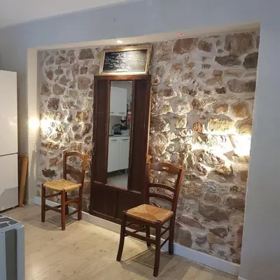 a stone wall with two chairs and a mirror at Horizon des Corbières in Saint-André-de-Roquelongue