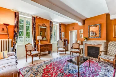 a living room with orange walls and a fireplace at Maison de famille Lafonsèque in Renneville