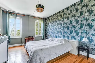 a bedroom with a bed and a floral wallpaper at Maison de famille Lafonsèque in Renneville