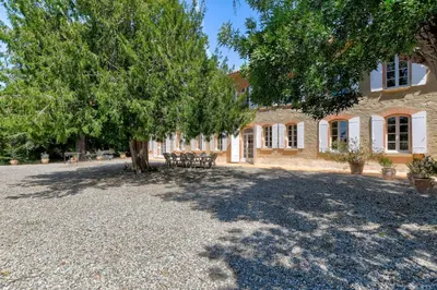a building with a tree and a table and chairs at Maison de famille Lafonsèque in Renneville