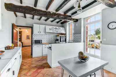 a kitchen with white cabinets and a table at Maison de famille Lafonsèque in Renneville