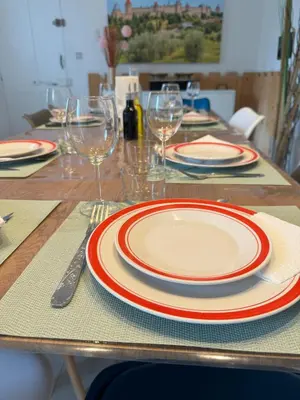 a table with red and white plates and wine glasses at La maison Auguste - vue imprenable sur la Cité in Carcassonne