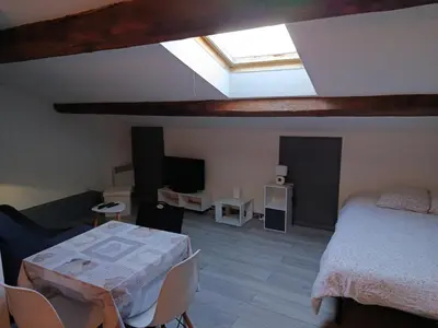 a bedroom with a bed and a table and a skylight at Grand studio proche centre in Narbonne