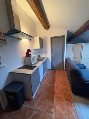 a small kitchen with a microwave and a couch at Grand studio proche centre in Narbonne