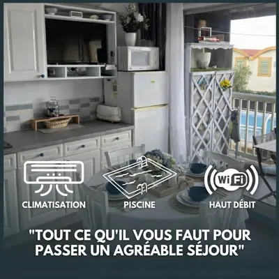 a kitchen with white cabinets and a stove top oven at Fleur Australe in Gruissan