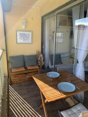 a patio with a wooden table and a couch at Fleur Australe in Gruissan