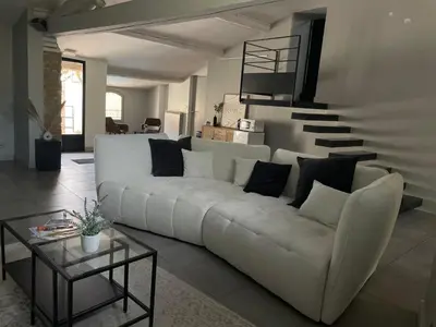 a living room with a white couch and a staircase at La Tuilerie du Bazalac in Trèbes