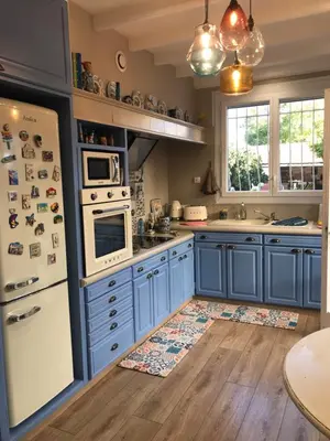 a kitchen with blue cabinets and a white refrigerator at Chez Martine Côté Cité in Carcassonne