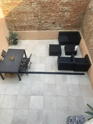 a patio with a black couch and a table at Cocon mazerien in Mazères