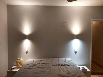 a bedroom with a bed and two lights on the wall at Cocon mazerien in Mazères