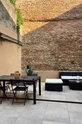 a patio with a table and chairs and a brick wall at Cocon mazerien in Mazères