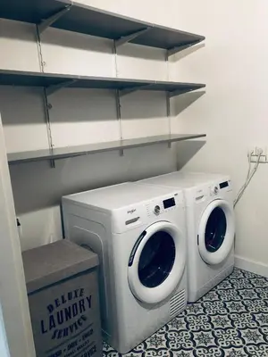 a washer and dryer in a laundry room with shelves at Cocon mazerien in Mazères