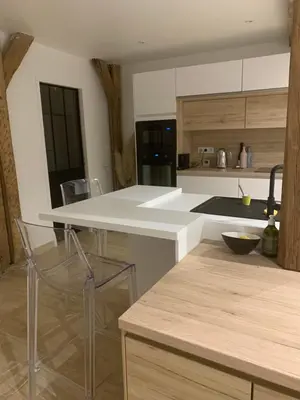 a kitchen with a white counter and chairs in it at Cocon mazerien in Mazères