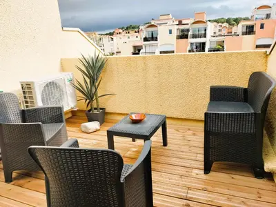 a patio with chairs and a table on a balcony at Le Quai401 YourHostHelper in Gruissan