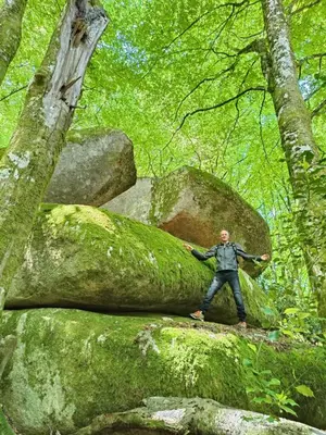 a man standing on a moss covered rock in a forest at L'oustal in Lacrouzette