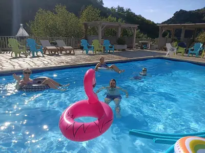 a group of people in a swimming pool with a pink swan in the water at L'oustal in Lacrouzette