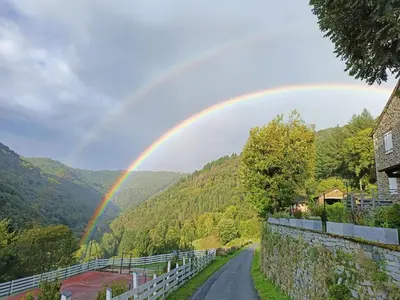 a rainbow in the sky over a road at L'oustal in Lacrouzette