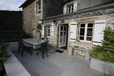 a patio with a table and chairs in front of a building at L'oustal in Lacrouzette