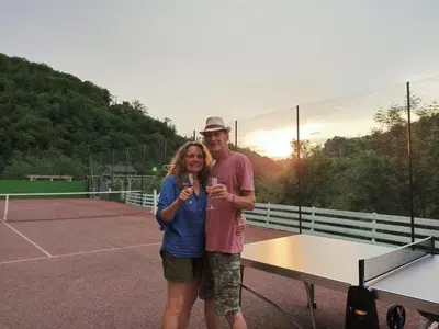 a man and a woman standing on a tennis court at L'oustal in Lacrouzette