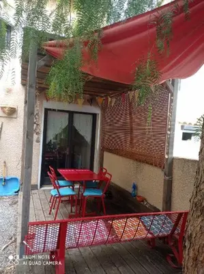a patio with a red table and chairs on a deck at Agréable maison de vacances in Port-la-Nouvelle