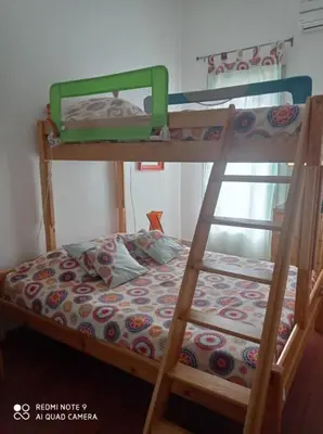 a bunk bed with a ladder and a bed with a mattress at Agréable maison de vacances in Port-la-Nouvelle