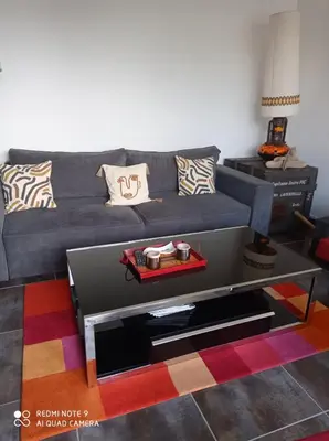 a living room with a gray couch and a coffee table at Agréable maison de vacances in Port-la-Nouvelle