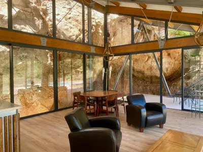 a room with a table and chairs and windows at Architect's house Cleopatra luxury , private pool in heart of nature for 2 people in Quarante