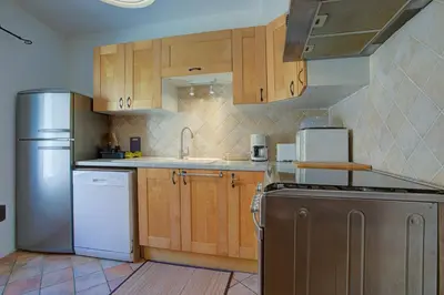a kitchen with wooden cabinets and a stainless steel refrigerator at L'Oustalet - Single-family home with terrace Oustalet in Ferrals-lès-Corbières