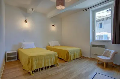 a room with two beds and a window and a chair at L'Oustalet - Single-family home with terrace Oustalet in Ferrals-lès-Corbières