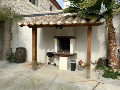 a pavilion with a table and a grill in front of a building at Vistetta in Narbonne