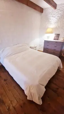 a bedroom with a white bed and a night stand at Le logis des vendangeurs in Puisserguier