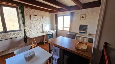 a small kitchen with a table and a counter top at Le logis des vendangeurs in Puisserguier