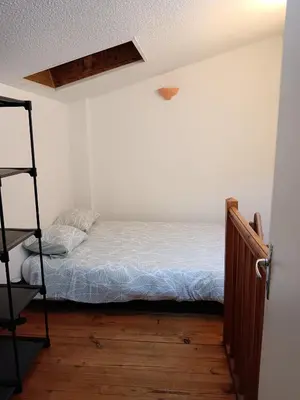 a small bedroom with a bed and a ladder at apt7 in Castelnaudary
