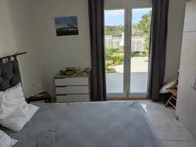 a bedroom with a bed and a sliding glass door at Maison proche mer - 5 couchages - ideal planchistes in Lapalme