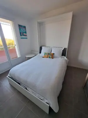 a bedroom with a large white bed with a window at studio proche Narbonne centre in Narbonne