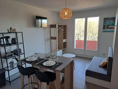 a living room with a table and some chairs at studio proche Narbonne centre in Narbonne