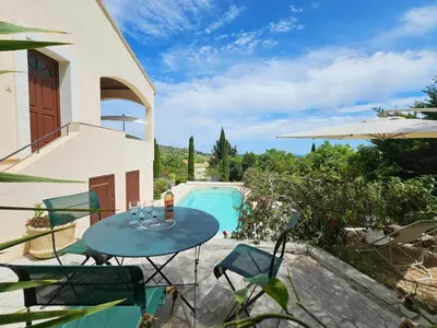 a patio with a table and chairs next to a pool at Sourire du Soleil in Montouliers
