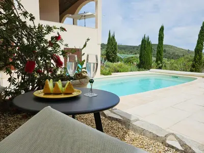 a table with a glass of wine next to a swimming pool at Sourire du Soleil in Montouliers