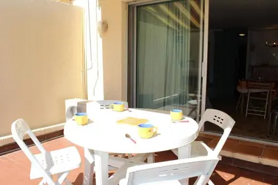 a white table with two chairs and cups on it at Appartement Studio Cabine - Gruissan GN110-C13 in Gruissan