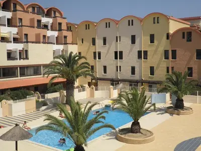 a view of a hotel with palm trees and buildings at Appartement 2 pièces cabine - Gruissan GN130-820 in Gruissan