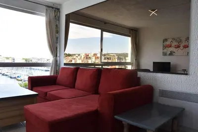 a living room with a red couch and a large window at Appartement évasion sur le port de Gruissan - GN380-C67 in Gruissan