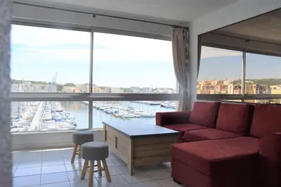 a living room with a red couch and a large window at Appartement évasion sur le port de Gruissan - GN380-C67 in Gruissan