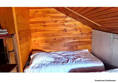 a bed in a room with a wooden wall at Maison QUÉRIGUT in Quérigut