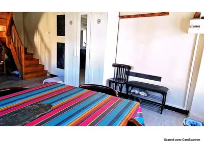 a room with a table and chairs and a staircase at Maison QUÉRIGUT in Quérigut