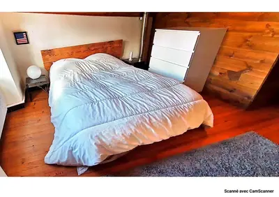 a bedroom with a bed and a wooden floor at Maison QUÉRIGUT in Quérigut