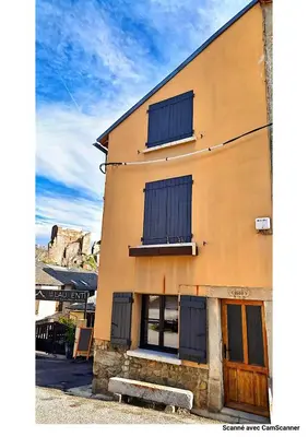 a yellow building with blue shutters on it at Maison QUÉRIGUT in Quérigut